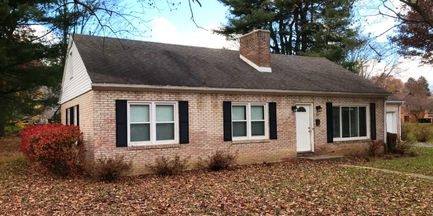 Exterior of light brick house, and black shutters