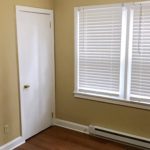 Bedroom with closet, window, and laminate, hardwood-style flooring