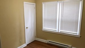 Bedroom with closet, window, and laminate, hardwood-style flooring