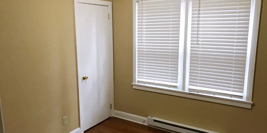 Bedroom with closet, window, and laminate, hardwood-style flooring