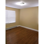 Bedroom with window and laminate, hardwood-style flooring