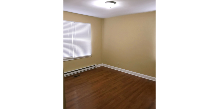 Bedroom with window and laminate, hardwood-style flooring