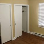 Bedroom with two closets, window, and laminate, hardwood-style flooring
