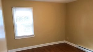 Bedroom with closet, window, and laminate, hardwood-style flooring