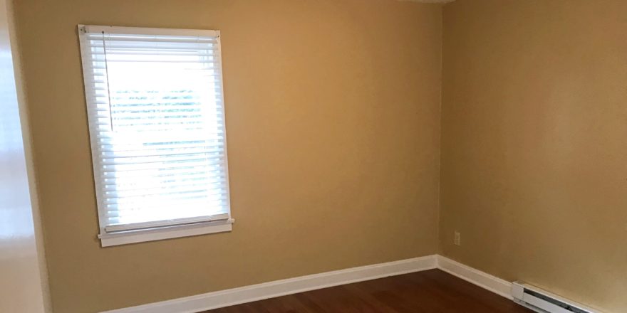 Bedroom with closet, window, and laminate, hardwood-style flooring