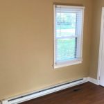 Bedroom with closet, window, and laminate, hardwood-style flooring