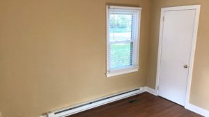 Bedroom with closet, window, and laminate, hardwood-style flooring