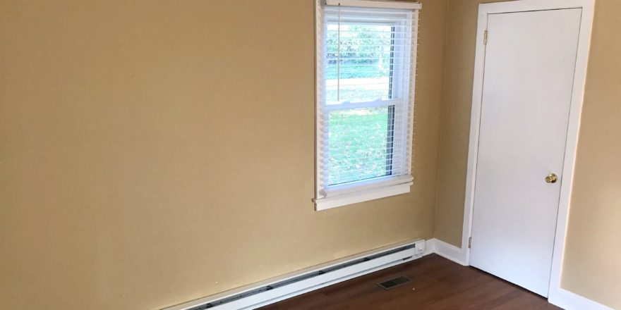 Bedroom with closet, window, and laminate, hardwood-style flooring