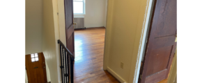 a hallway with a door and a wooden floor
