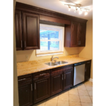 Kitchen with tile floor, dishwasher, double sink and cabinets