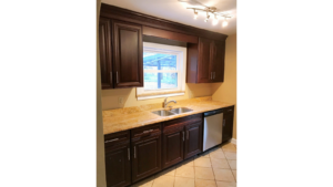 Kitchen with tile floor, dishwasher, double sink and cabinets