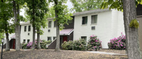 back exterior of galenwood showing a white painted building surrounded by trees, flowers and bushes