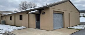 a tan building with a garage and snow on the ground