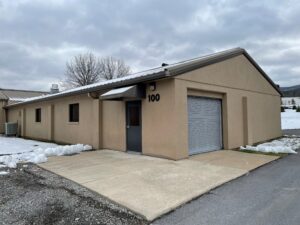a tan building with a garage and snow on the ground
