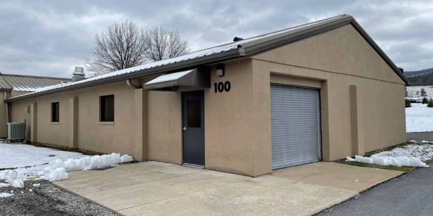 a tan building with a garage and snow on the ground