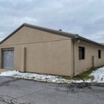 a tan building with two garages on the side of it