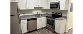 a kitchen with white cabinets and silver appliances