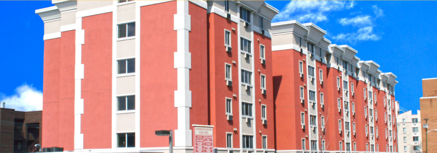 a red and white apartment building next to a parking lot