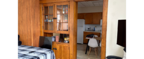 a bedroom with a bed, desk, and cupboards