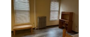 a bedroom with a bed, desk, and a radiator