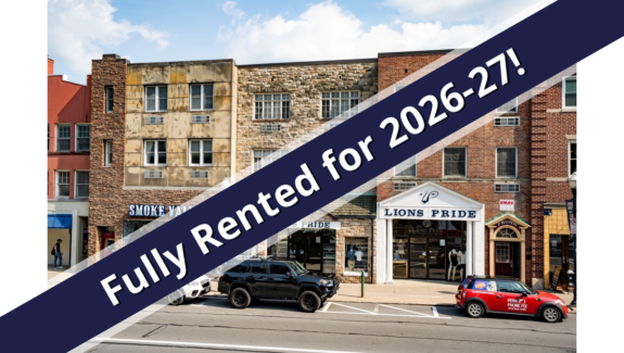 a red car driving down a street next to tall buildings