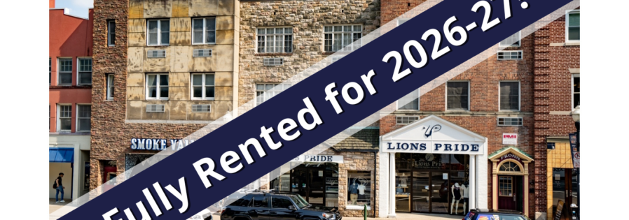 a red car driving down a street next to tall buildings