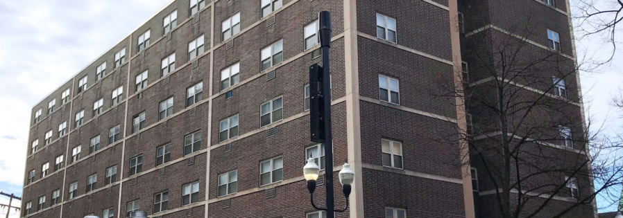 a tall brick building with windows and a red sign that says 2 bedroom available