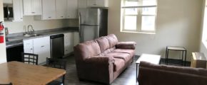 Living room and kitchen with stainless steel appliances, white cabinets, couch, love seat, accent tables, and dining table