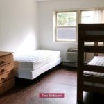 Carpet with wood-style floors with twin bed and bunk bed and wooden chests of drawers