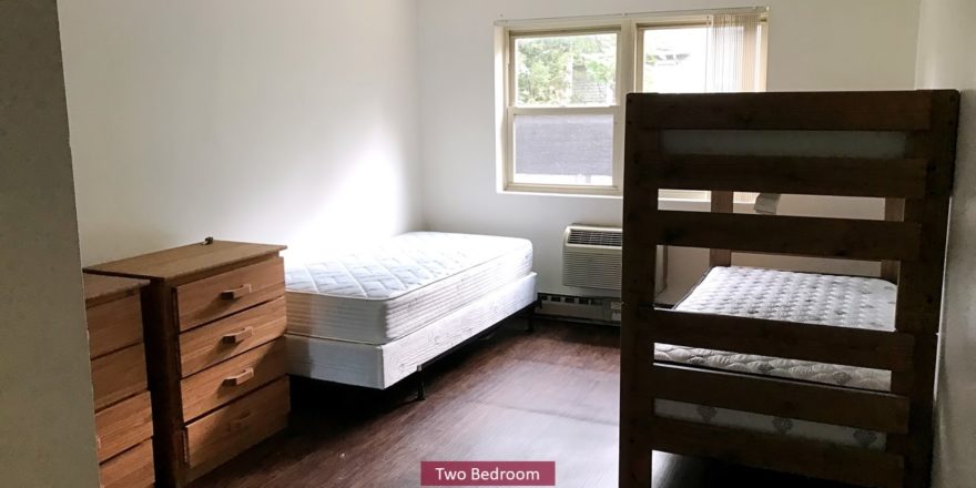 Carpet with wood-style floors with twin bed and bunk bed and wooden chests of drawers