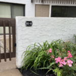 a white building with a gate and flowers in front of it