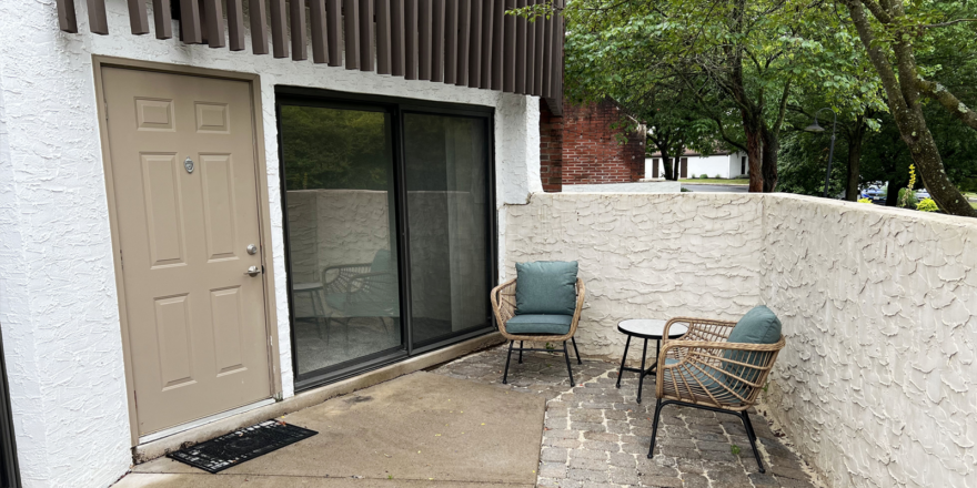 two chairs sitting on a patio next to a door