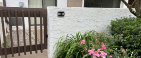 a white building with a gate and flowers in front of it