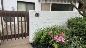 a white building with a gate and flowers in front of it