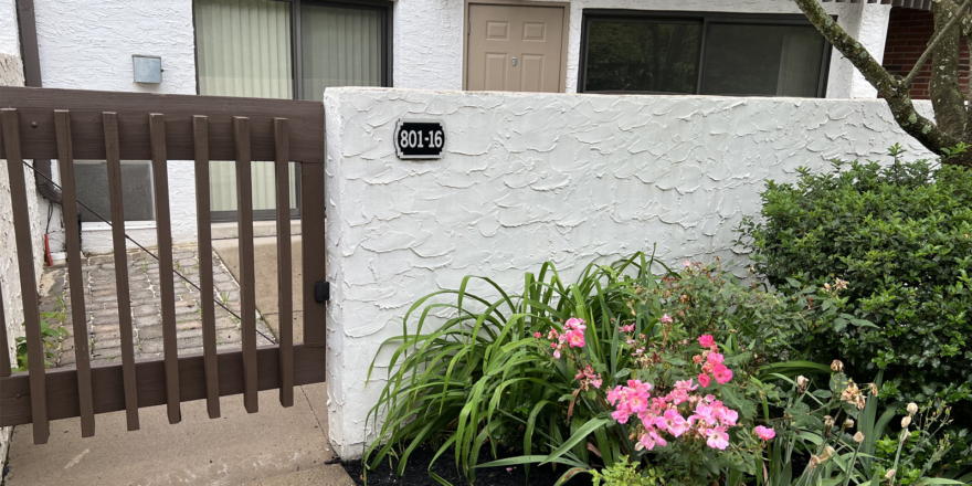 a white building with a gate and flowers in front of it