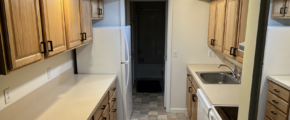 a narrow kitchen with wooden cabinets and white appliances