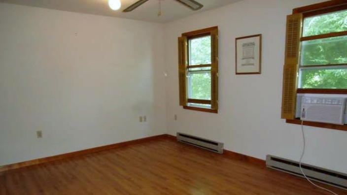 Unfurnished bedroom with window AC unit, ceiling fan, and hardwood floors