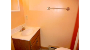 Half-bathroom with toilet, vanity, and mirror