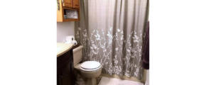 Bathroom with vanity, toilet, tub/shower combo and cabinet storage above toilet