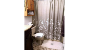 Bathroom with vanity, toilet, tub/shower combo and cabinet storage above toilet