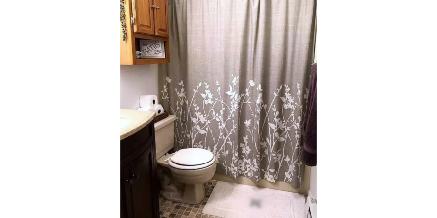 Bathroom with vanity, toilet, tub/shower combo and cabinet storage above toilet