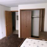 Carpeted, furnished bedroom with dresser, bed, and closet