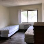 Bedroom with LVT flooring, 2 beds, 2 dressers, window, and AC unit