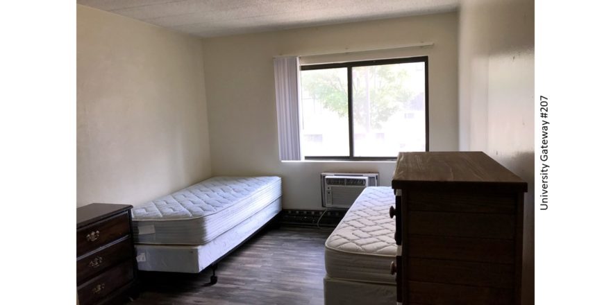 Bedroom with LVT flooring, 2 beds, 2 dressers, window, and AC unit