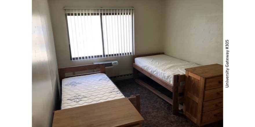 Carpeted bedroom with 2 beds, 2 dressers, window, and AC unit