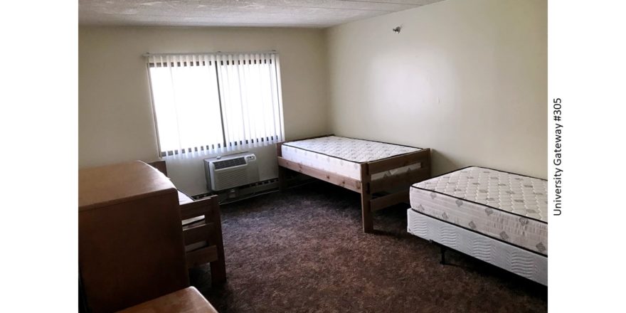 Carpeted bedroom with 3 beds, 2 dressers, window, and AC unit