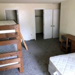 Carpeted bedroom with bunk bed, regular bed, desk with chair, walk-in closet, and en-suite bathroom