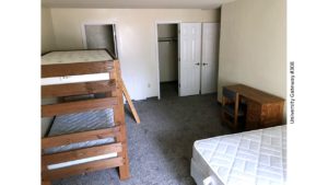 Carpeted bedroom with bunk bed, regular bed, desk with chair, walk-in closet, and en-suite bathroom