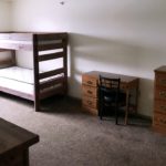 Carpeted bedroom with bunk bed, desk with chair, and two dressers