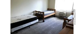 Carpeted bedroom with three beds, two dressers, AC unit, and window